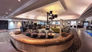 A spacious lobby with a curved seating area, a bar, and a television screen. - ORIDA Hotels Newbury (Newbury)
