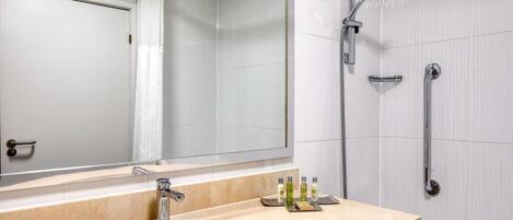 A modern bathroom with a sink, mirror, and shower.