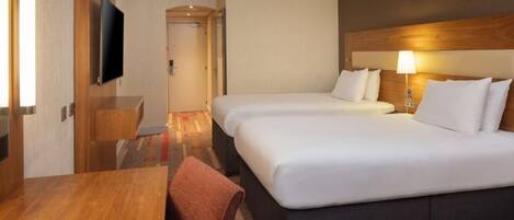 Una habitación de hotel con cama, mesitas de noche, televisor y lámpara.