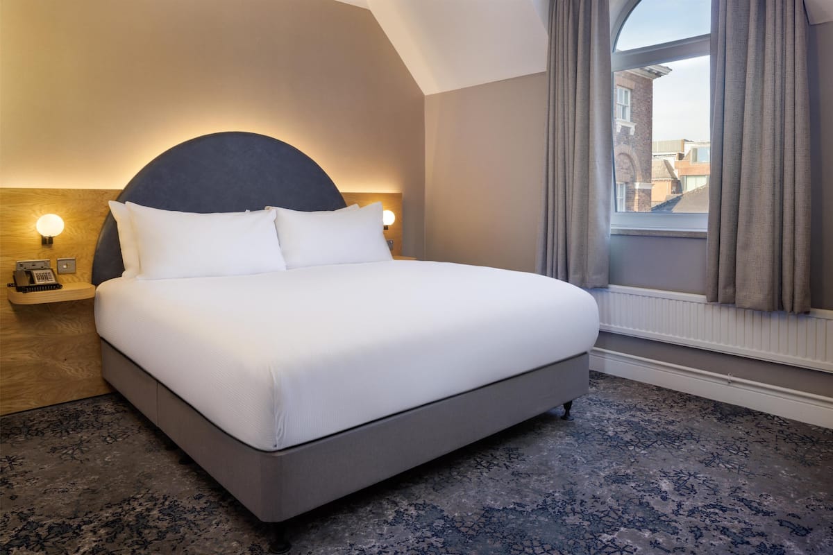 A neatly made bed with white linens in a hotel room.