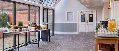 A modern kitchen with a large window, a dining area with a long table, and a small bar area with a drink dispenser.
