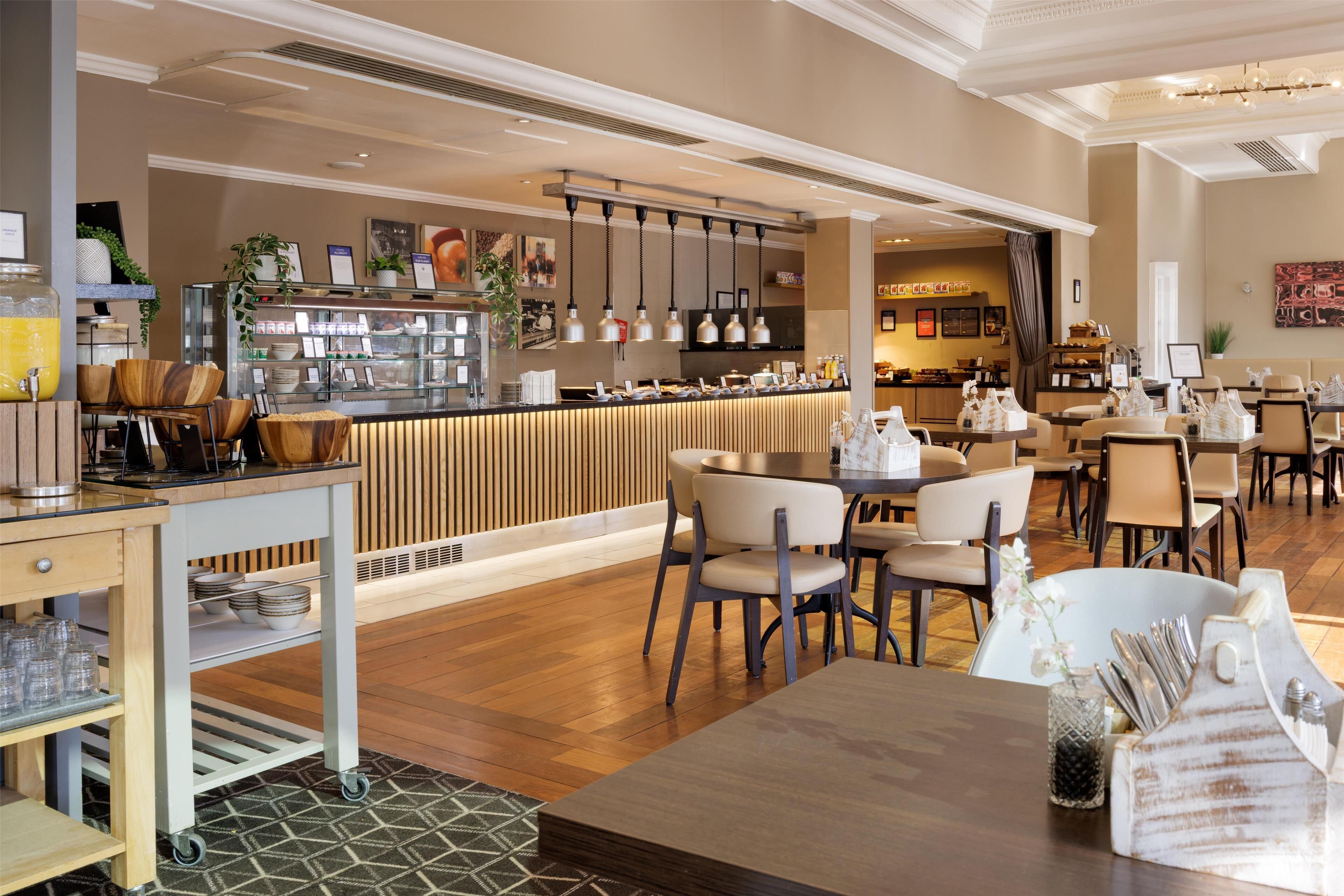 A modern restaurant with a bar area, wooden furniture, and a variety of seating options.