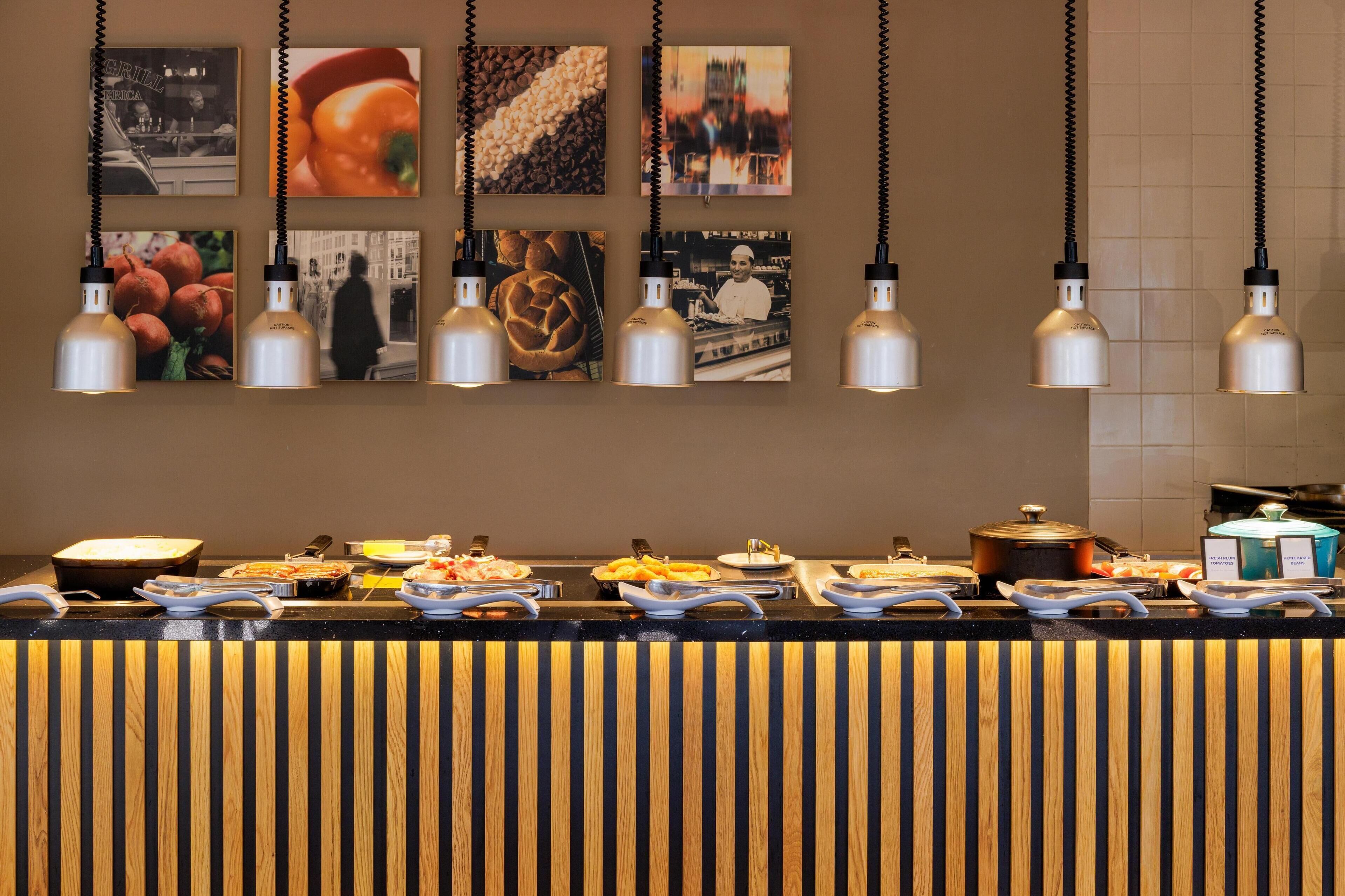 Zona de bufé con diferentes opciones de comida e iluminación colgante.