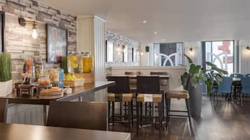 Una cocina moderna con un rebozo de ladrillo, una zona de bar con taburetes y un comedor con sillas azules.