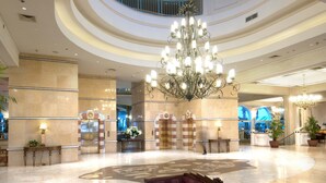 A spacious lobby with a grand chandelier, a central seating area, and a circular floor design. - Herods Palace Hotel (Eilat)