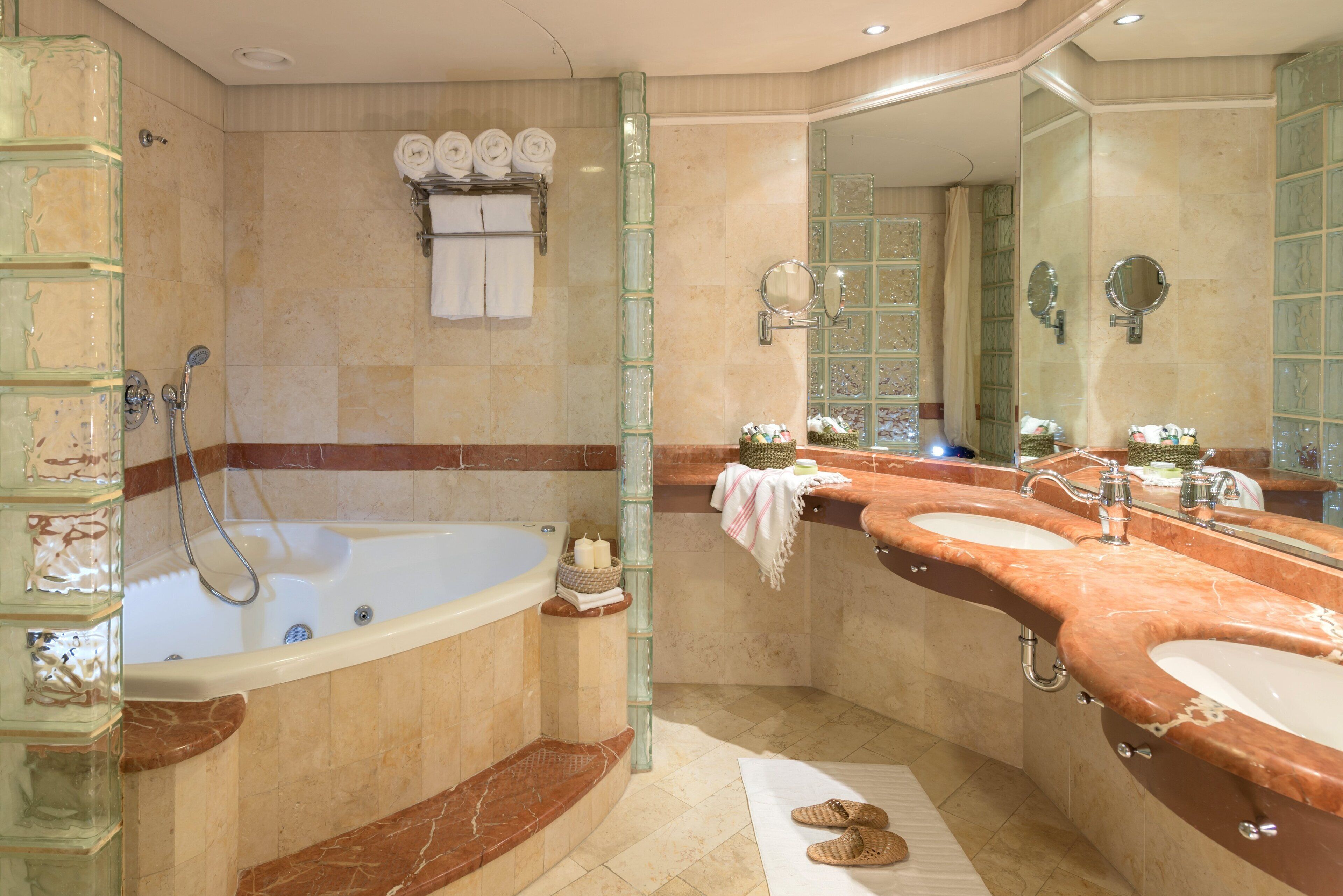 Un baño con una bañera grande, dos lavamanos y un espejo.
