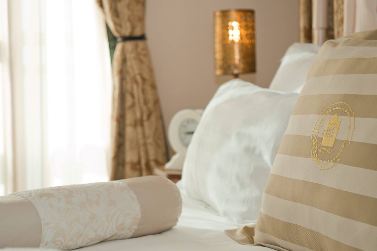 A hotel room with a bed, a lamp, and curtains.