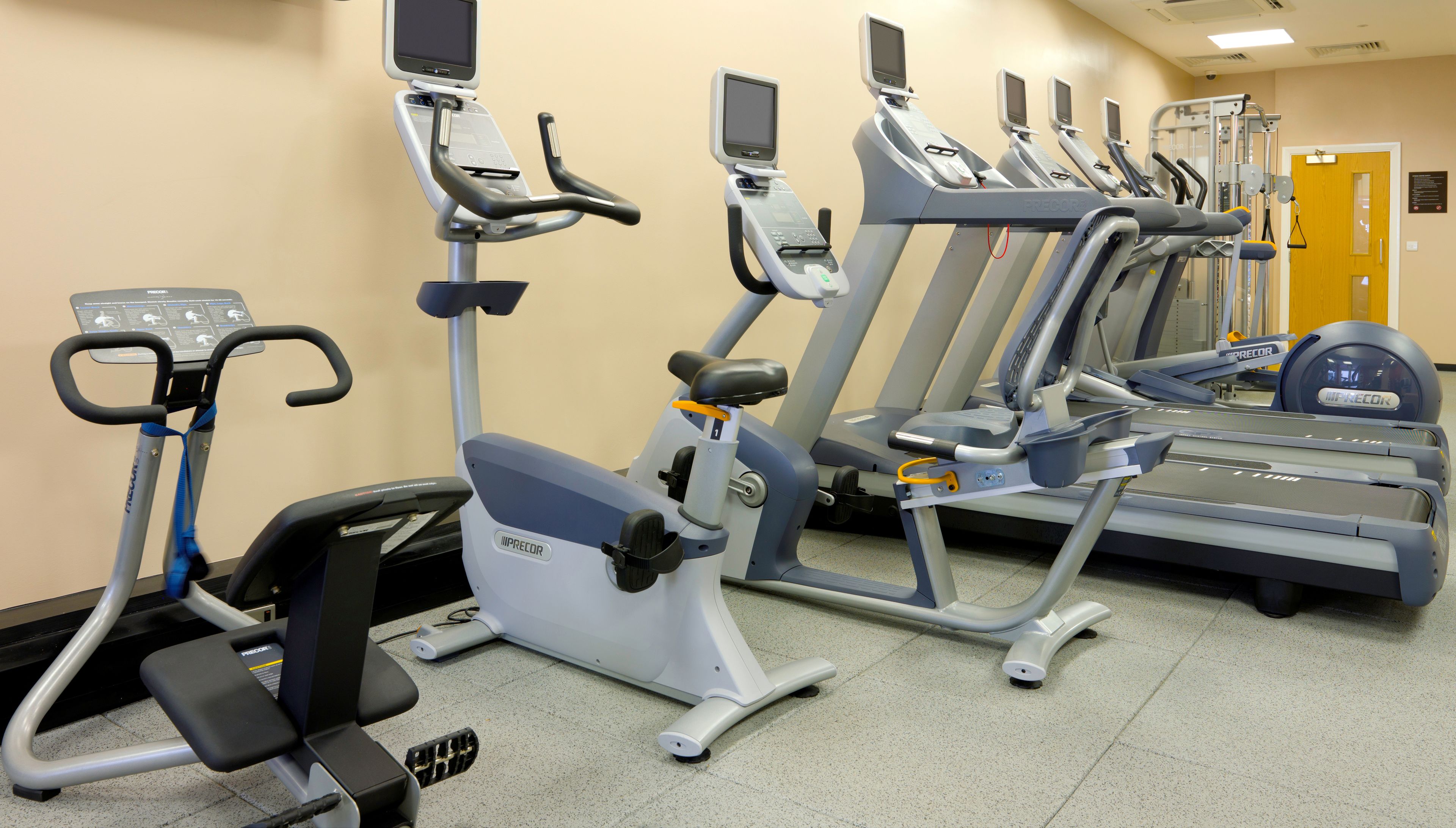 A gym with various exercise machines including treadmills, ellipticals, and a stationary bike.