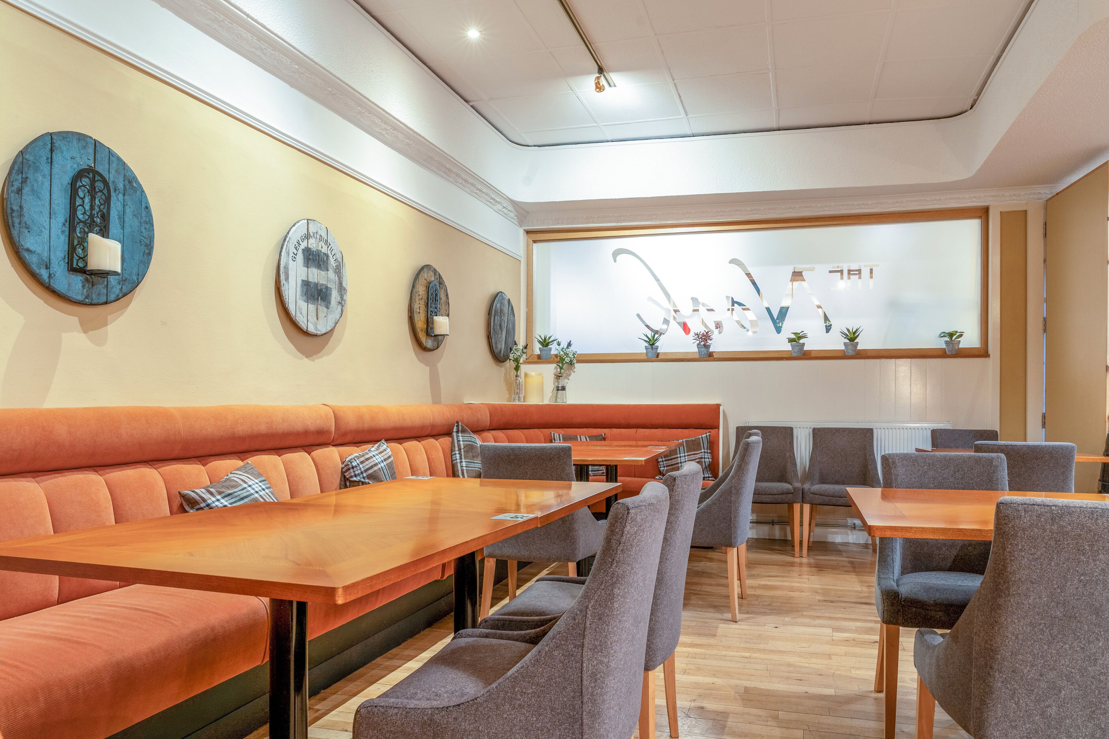 Un ristorante con un lungo tavolo in legno e sedute imbottite.