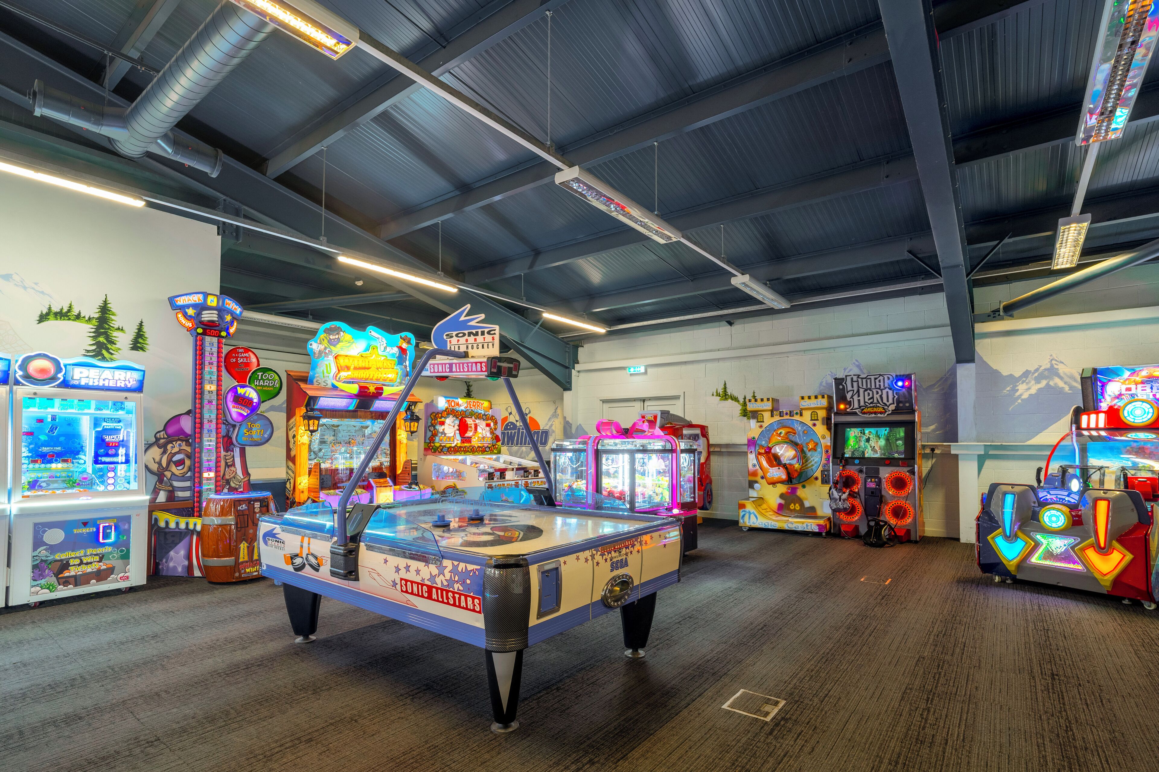 An indoor arcade with various gaming machines, including a prominent 'Sonic Allstars' game.