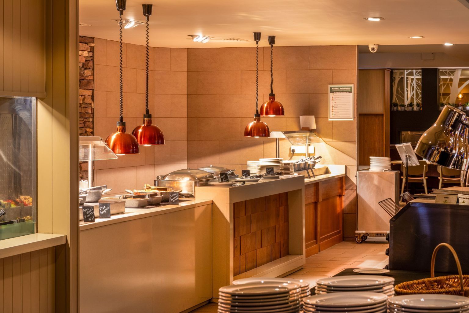 A modern kitchen area with a buffet setup, including a counter with food items and a sign indicating a coffee station.
