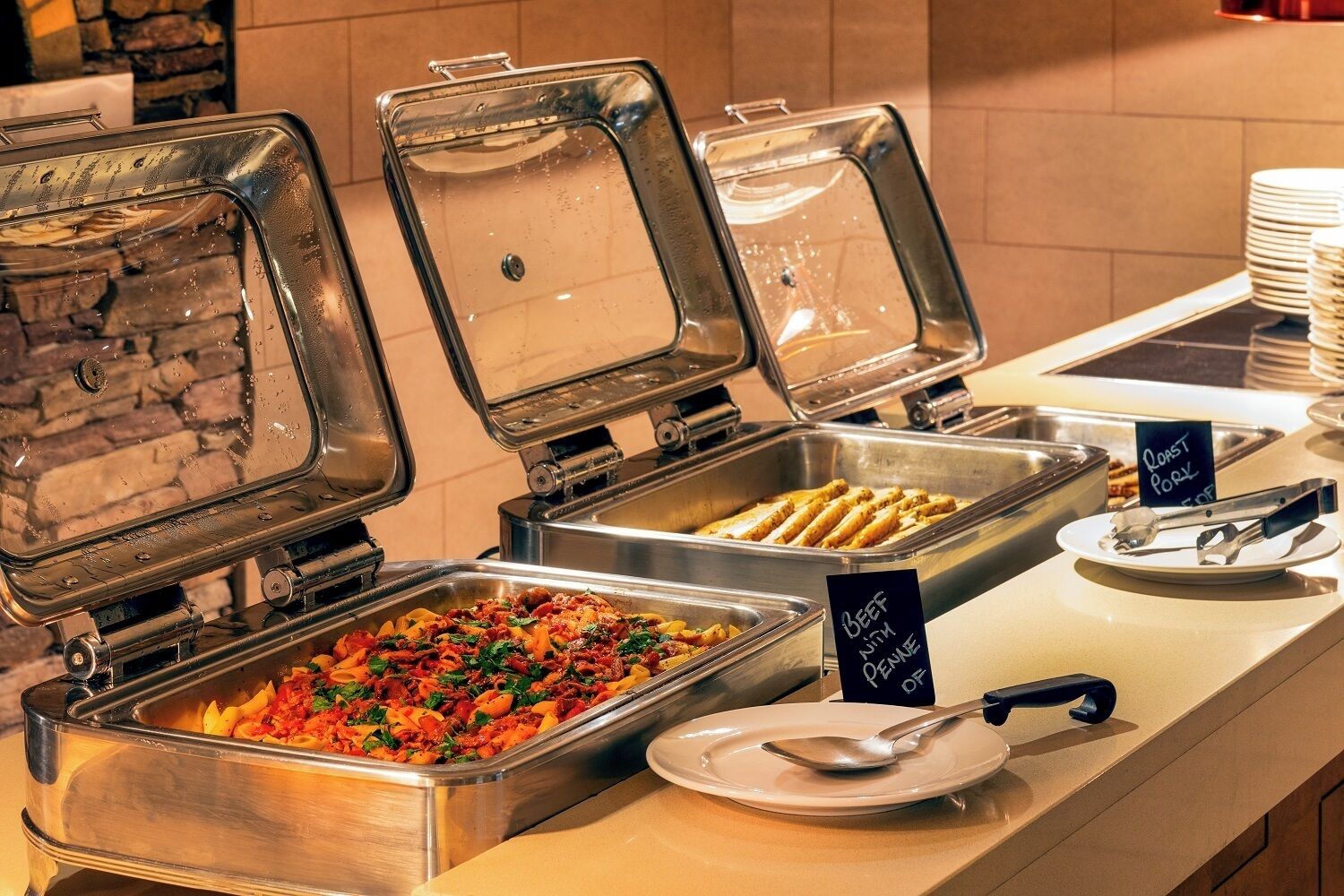 A buffet with various food options including pasta, roast pork, and beef with Parmesan.