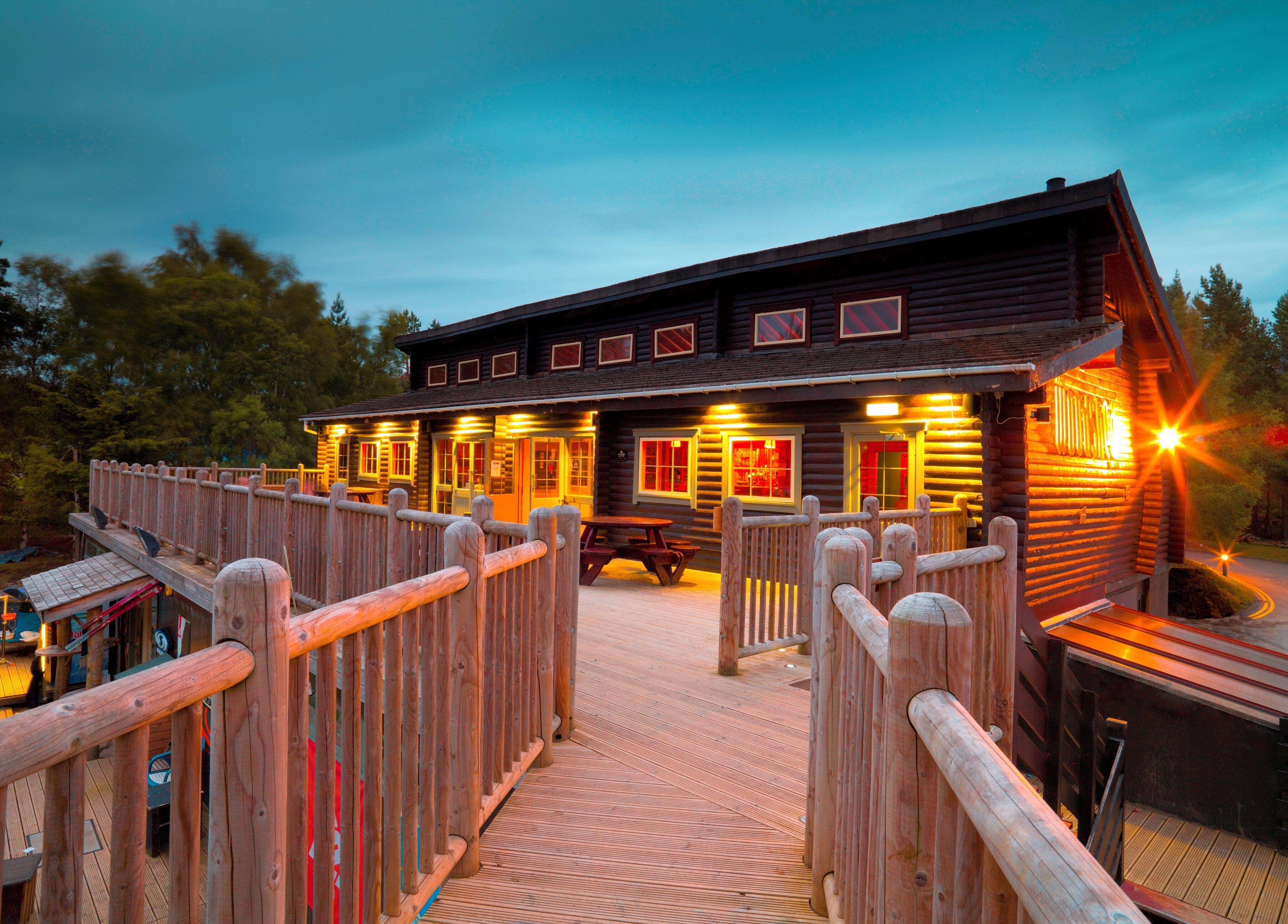 Een houten chalet met een terras en een overdekte picknickplaats.
