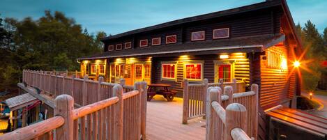 Een houten chalet met een terras en een overdekte picknickplaats.
