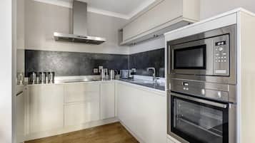 Una cocina moderna con armarios blancos, una campana extractora de acero inoxidable, un microondas y un horno.