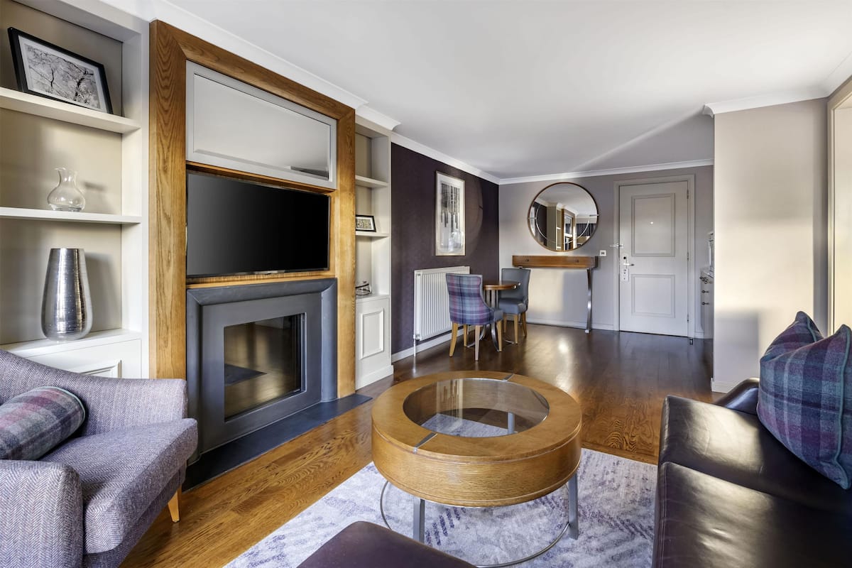 A modern living room with a fireplace, round coffee table, and seating area.