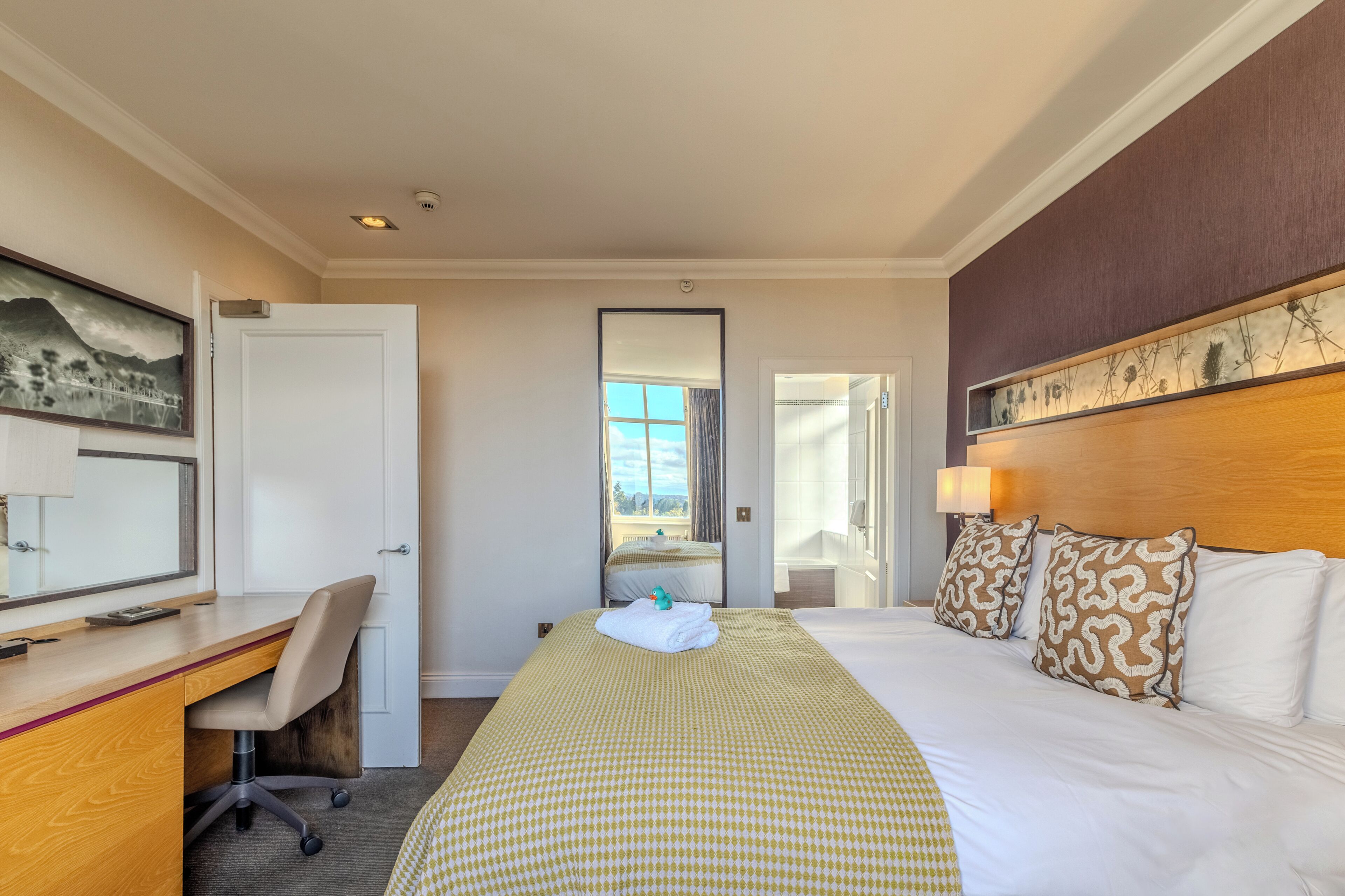 Une chambre d’hôtel avec un lit, un bureau et une vue sur l’extérieur par une fenêtre.