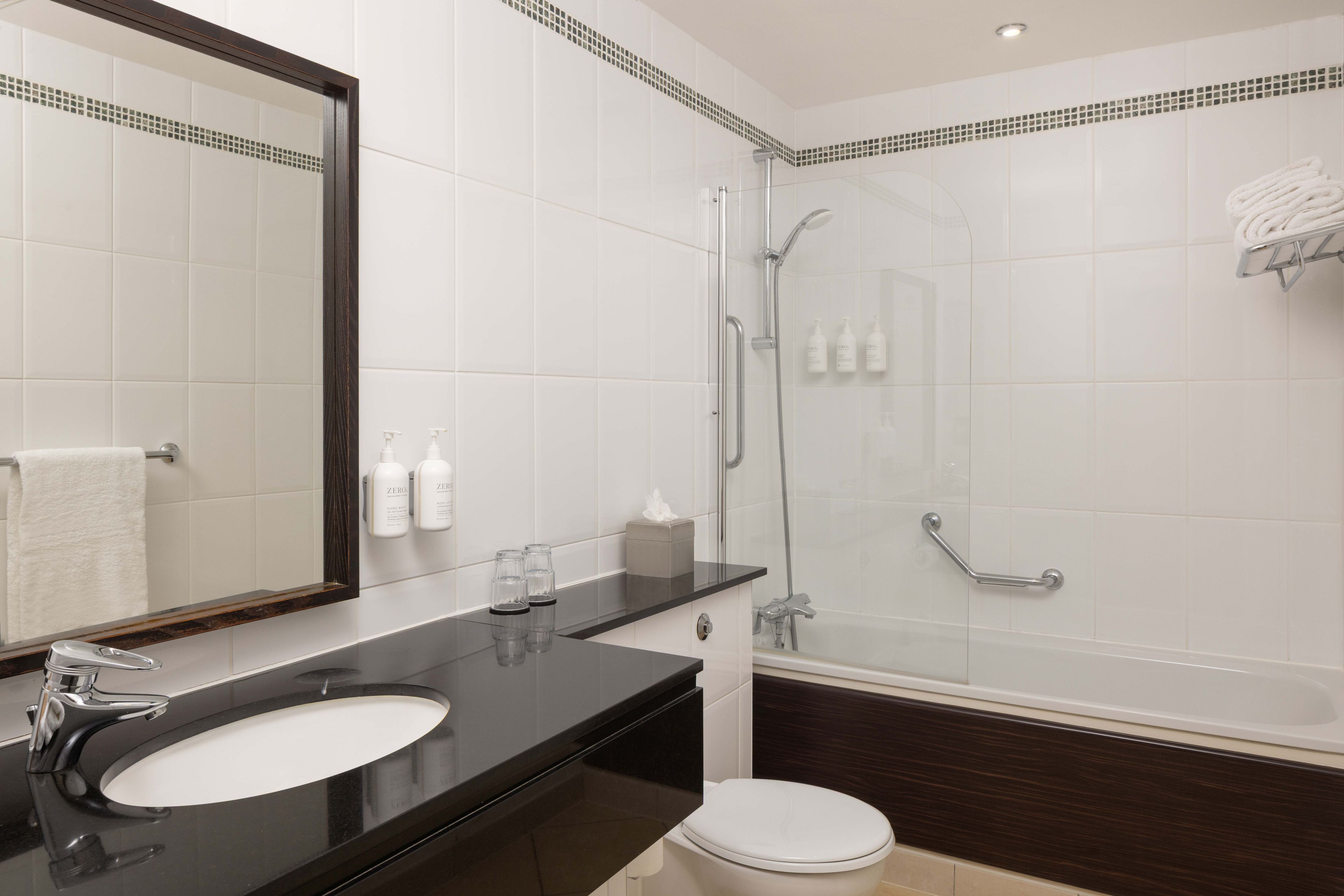 A modern bathroom with a black sink, a mirror, a toilet, and a glass-enclosed shower area.
