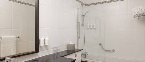 A modern bathroom with a black sink, a mirror, a toilet, and a glass-enclosed shower area.