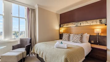 A hotel room with a large bed, a chair, a small table, and a view of the outdoors.
