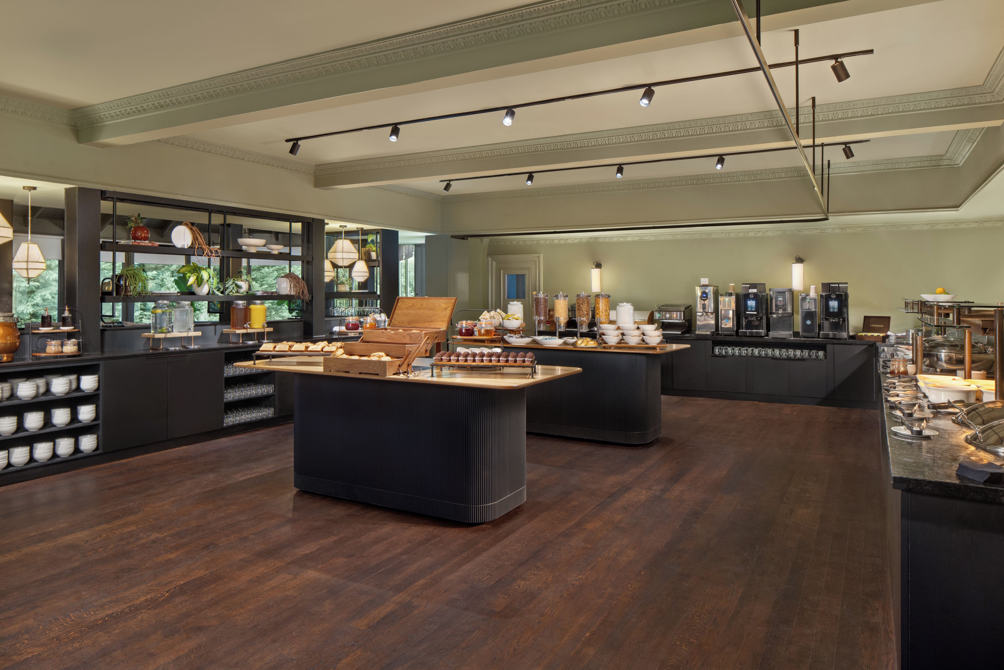 A modern breakfast area with a variety of food options, including pastries and beverages, and a coffee station.