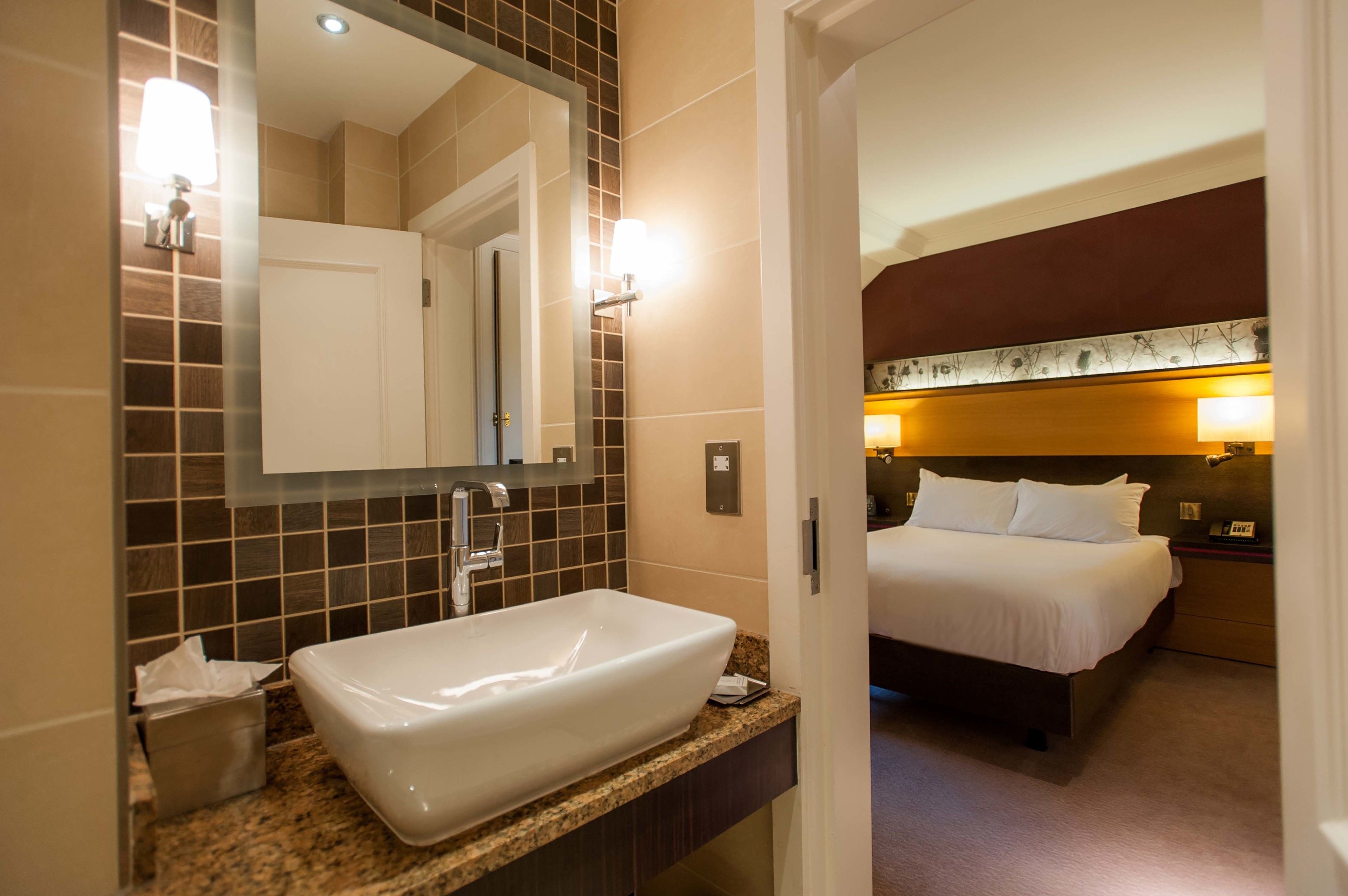 Een hotelbadkamer met een groot wit wastafel, een spiegel en een toilet.