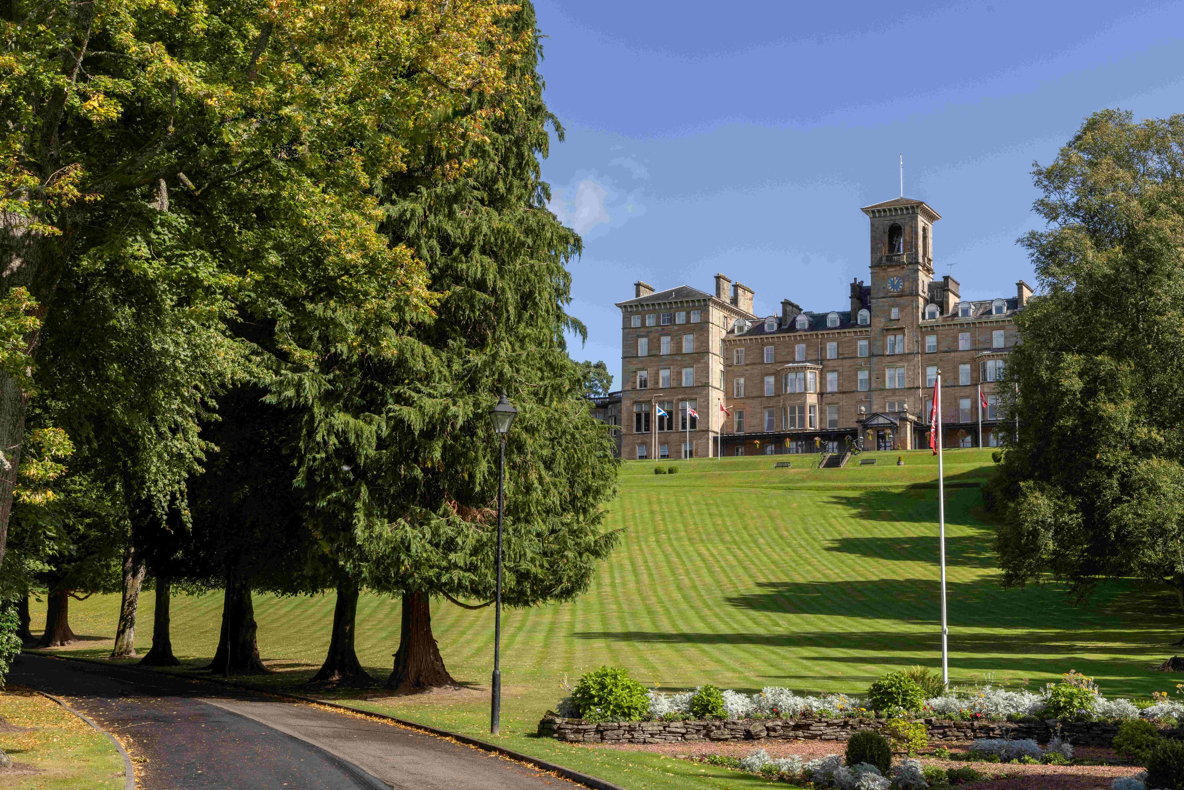 A large building with a clock tower, surrounded by a well-maintained lawn and trees.