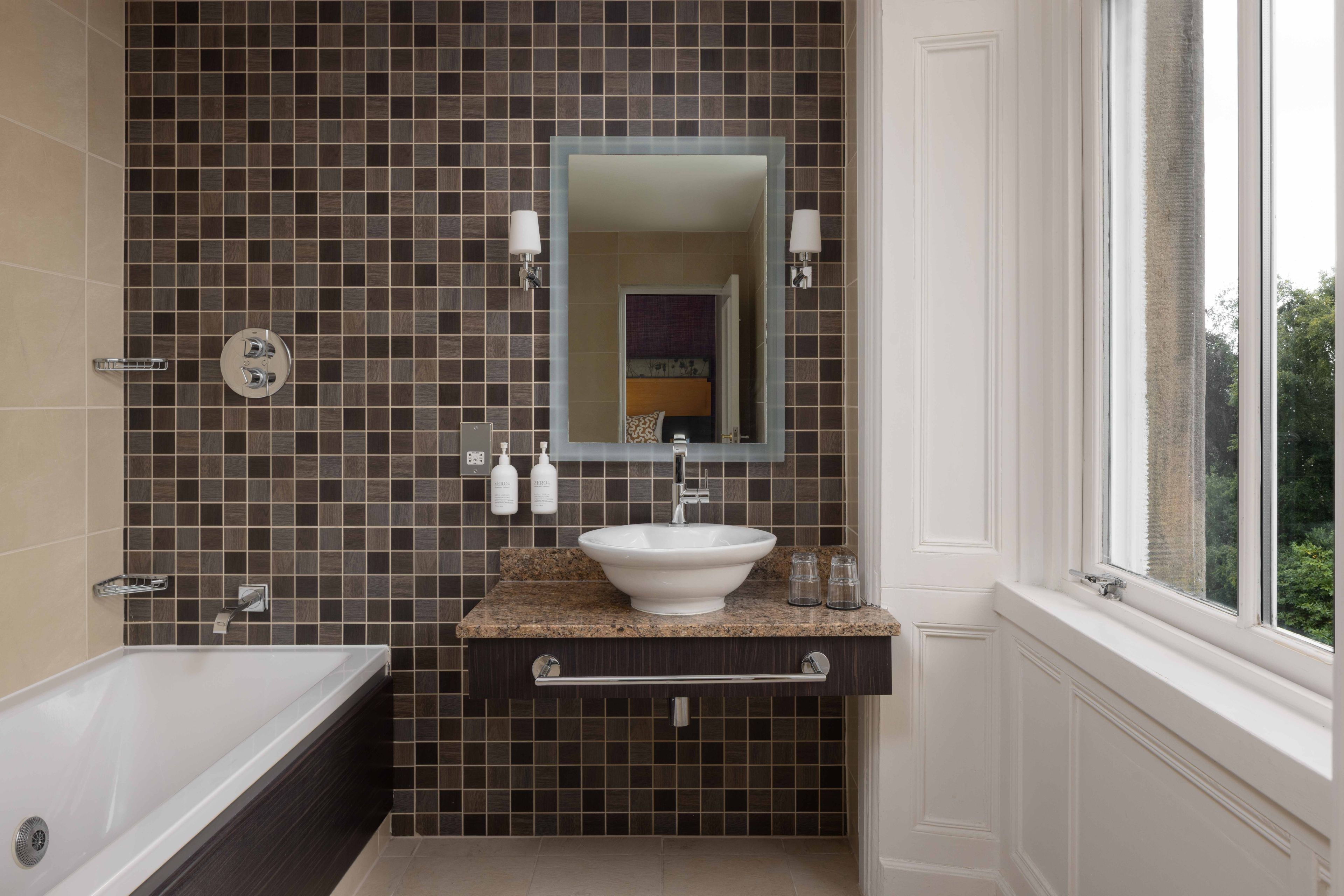 A bathroom with a bathtub, a sink, and a mirror.