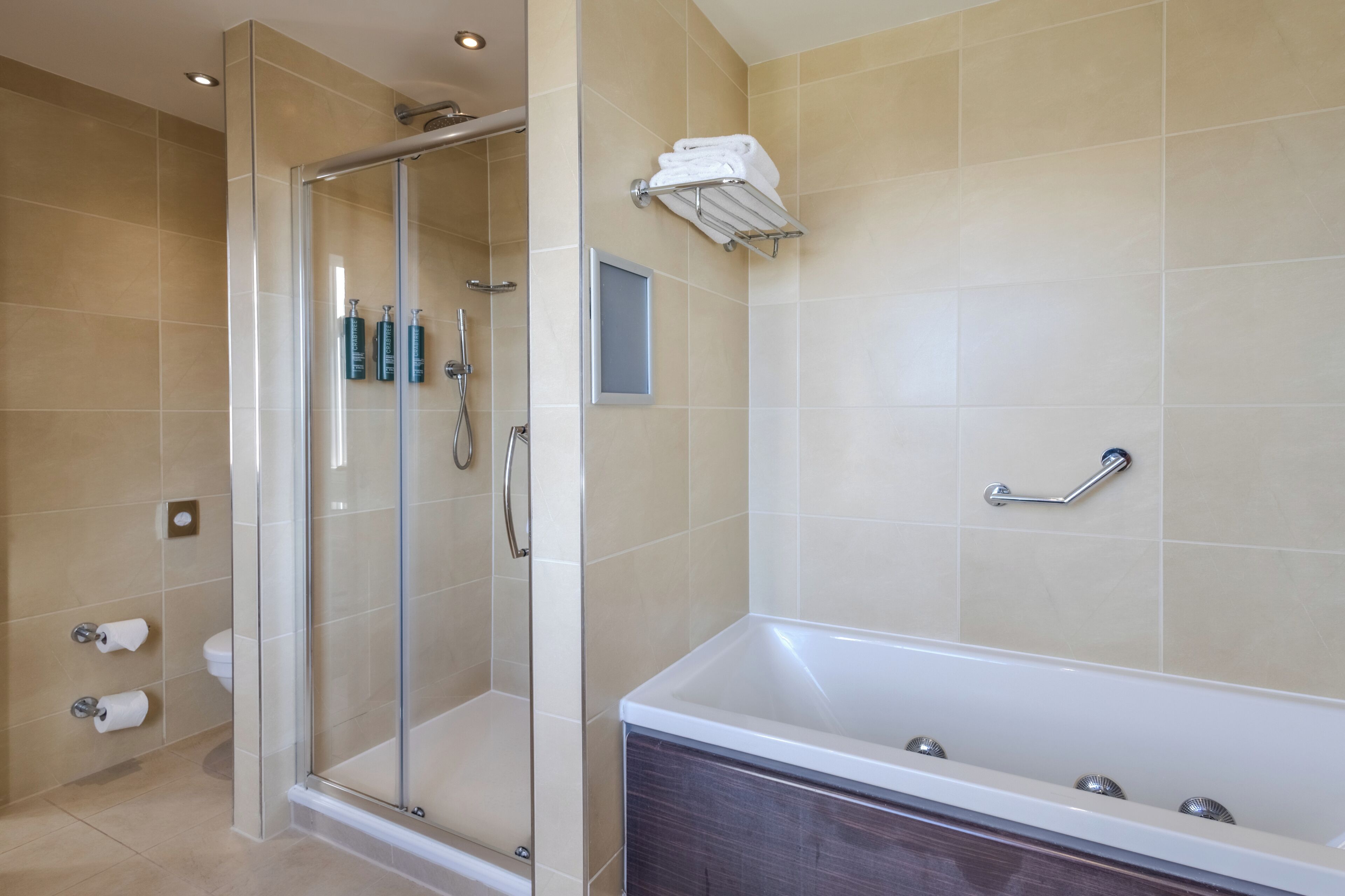 A modern bathroom with a glass-enclosed shower, a bathtub, and a towel rack.