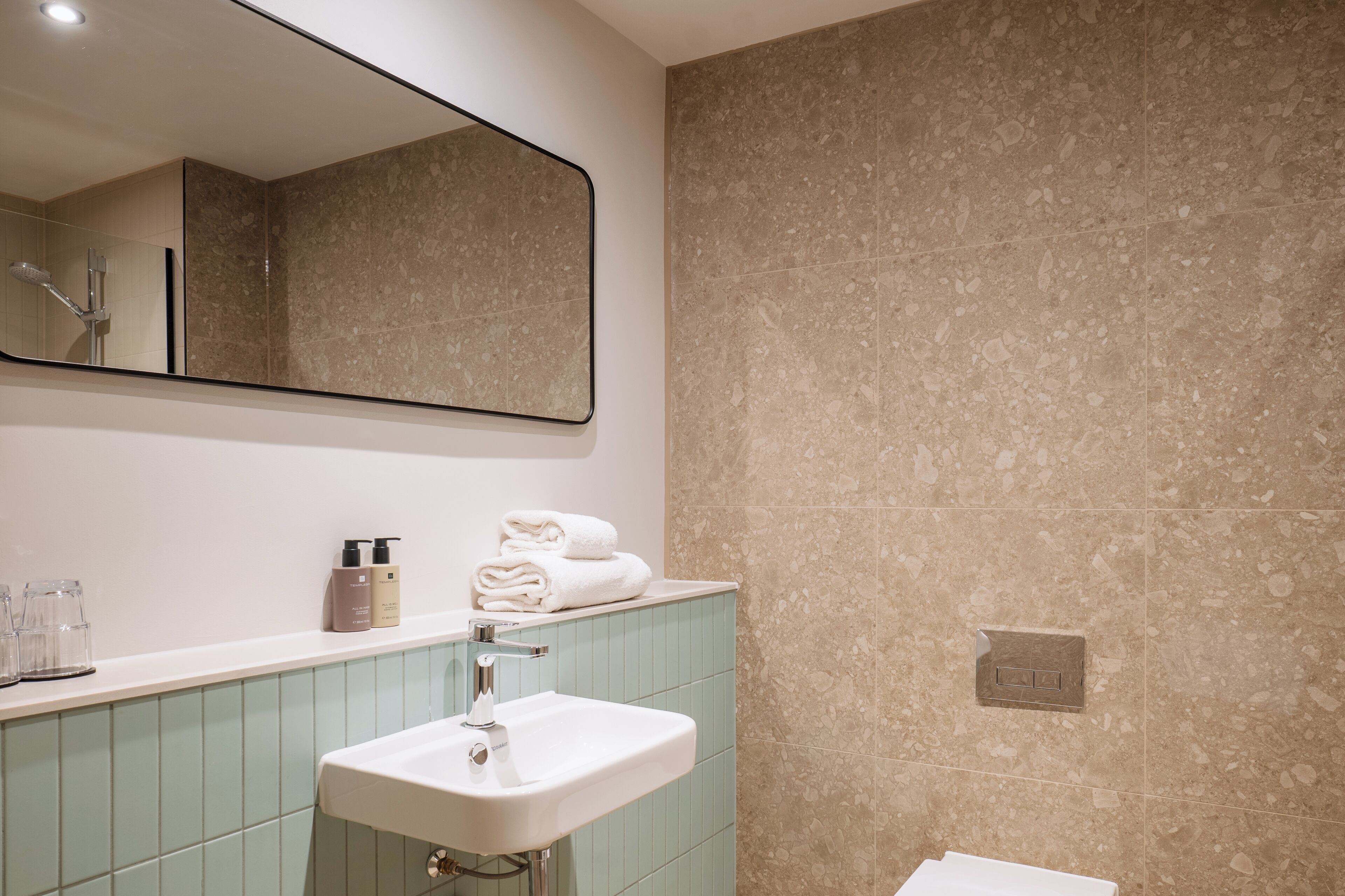 Une salle de bain avec un lavabo, un miroir et des murs carrelés.