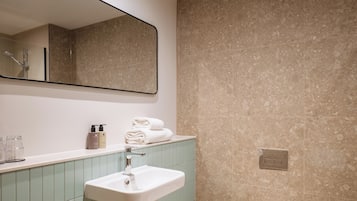 Une salle de bain avec un lavabo, un miroir et des murs carrelés.