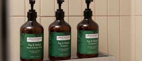 Three bottles of Antipodes Fig & Feijoa Hand & Body Wash on a white shelf against a tiled wall.