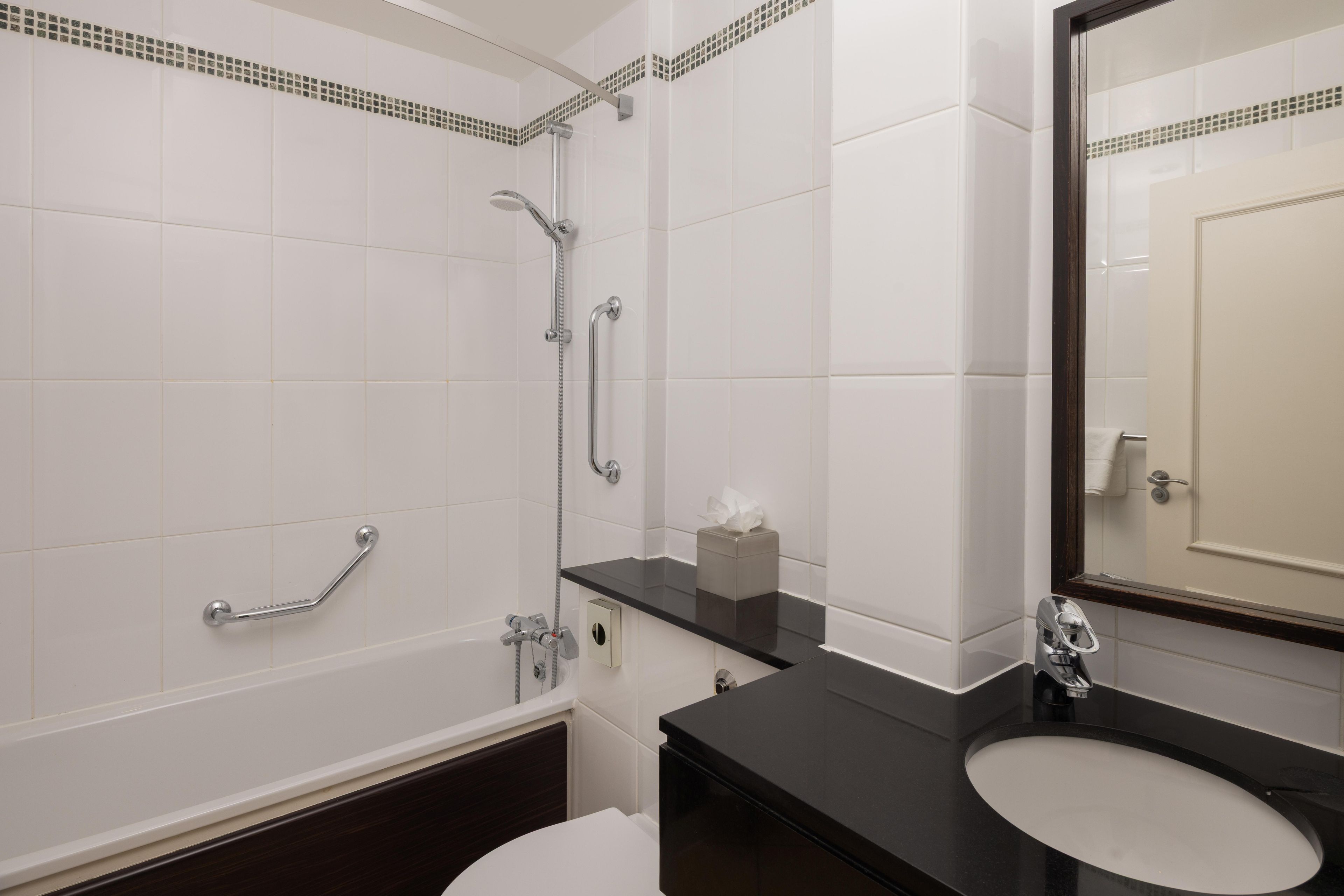 Une salle de bain avec une baignoire, des toilettes, un lavabo et un miroir.