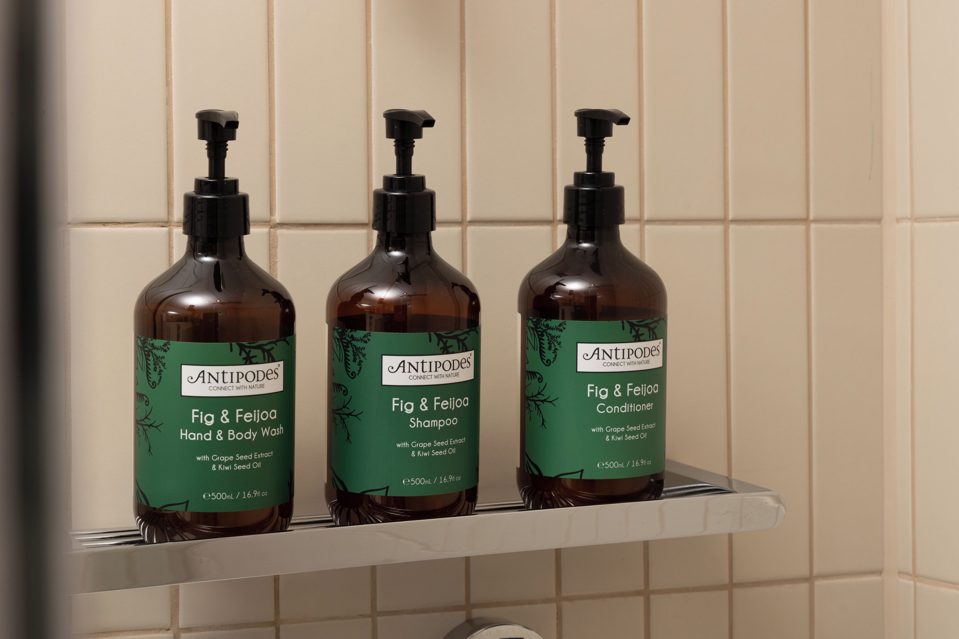 Three bottles of Antipodes Fig & Feijoa Hand & Body Wash on a white shelf.