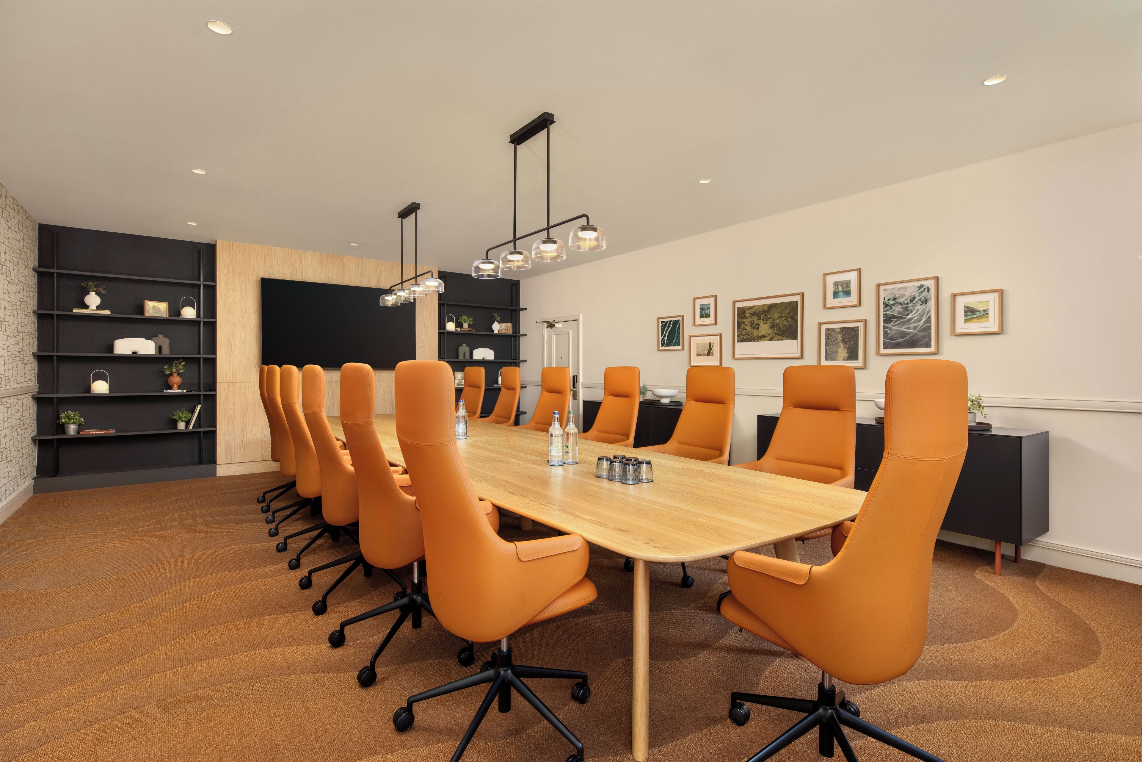 A conference room with a long table, multiple chairs, and a modern ceiling light fixture.