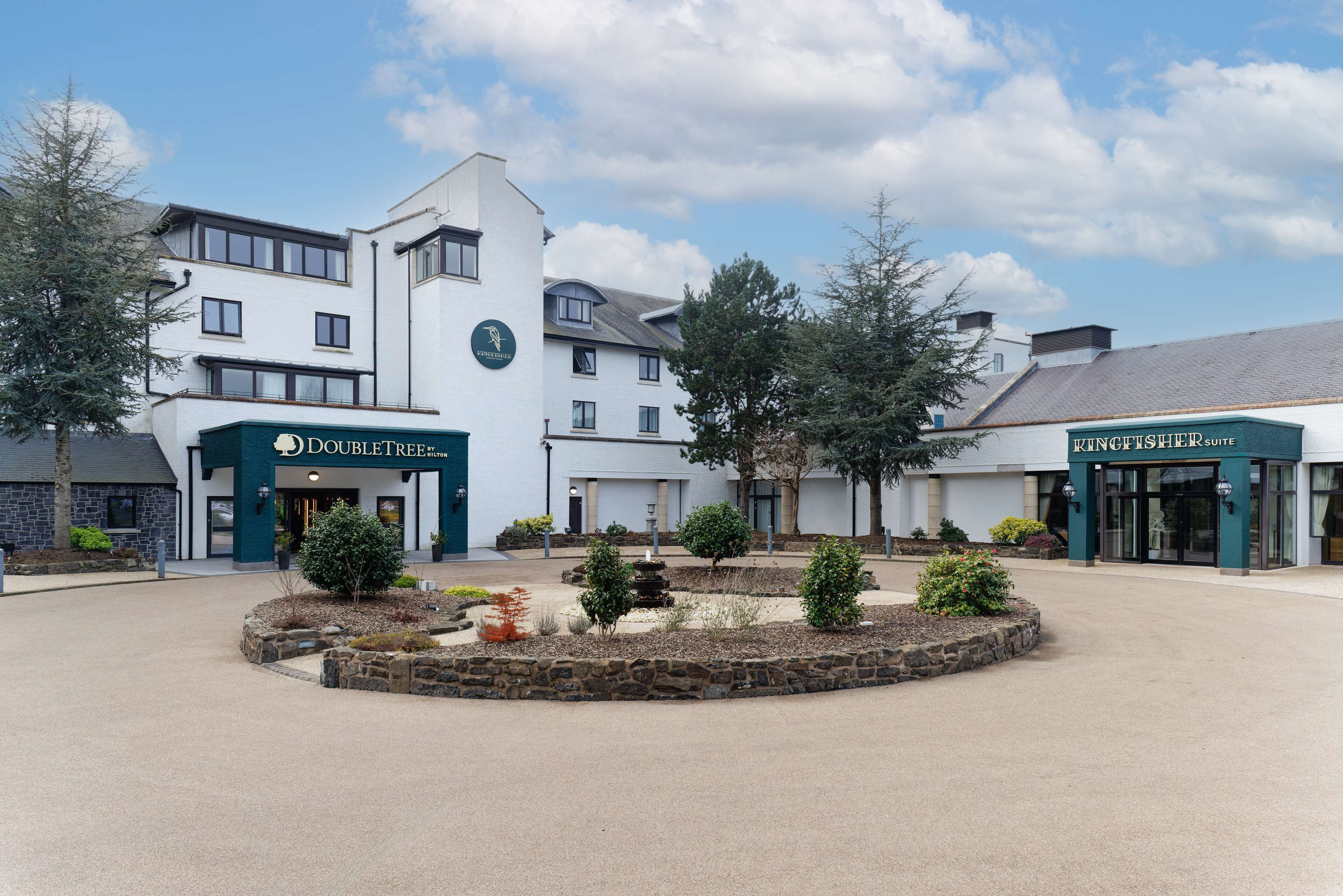 A hotel with a central courtyard, DoubleTree and Vinglisher Suite signs, and a stone fountain.