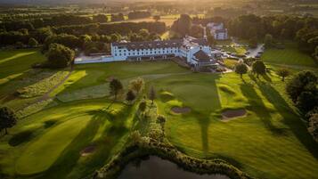 An aerial view of a golf course with a large building complex, including a clubhouse and multiple structures.