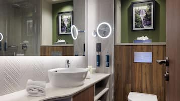 A modern bathroom with a large mirror, a white sink, and a toilet.