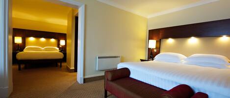 Una habitación de hotel con una cama grande, un banco y dos lámparas de noche.