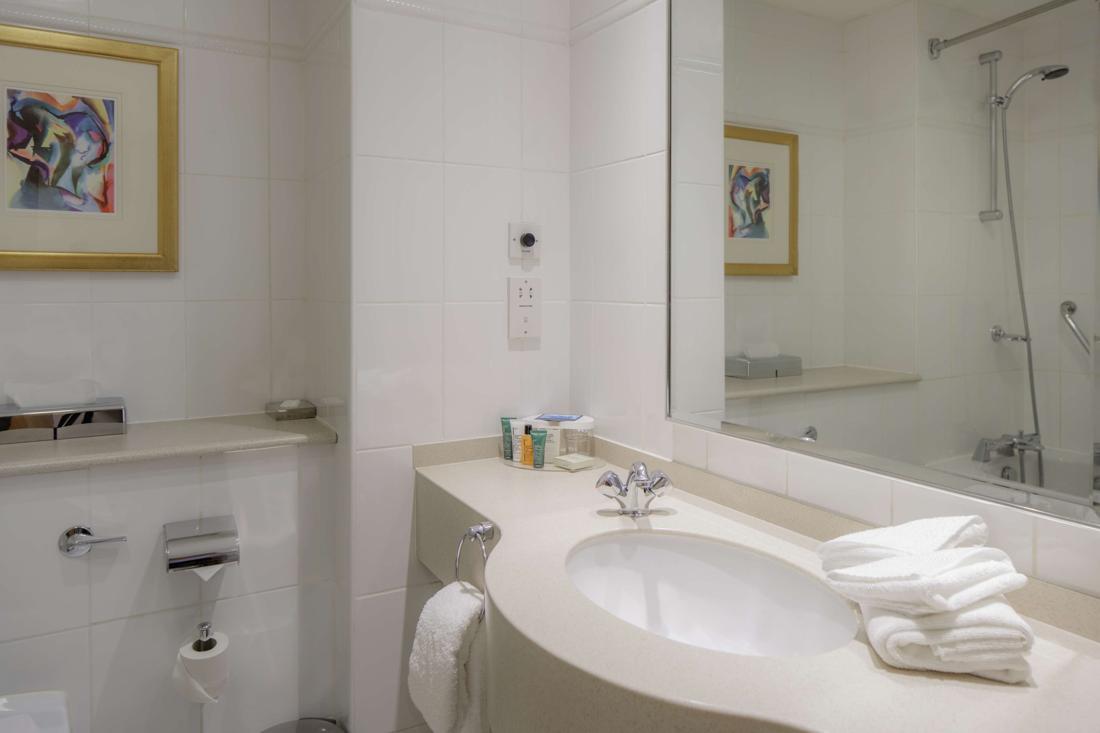 Un baño moderno con un lavamanos grande, espejo y ducha.