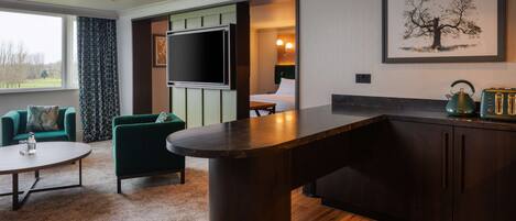 Una habitación de hotel moderna con un televisor de pantalla plana grande, una zona de comedor con bar y vistas al exterior.