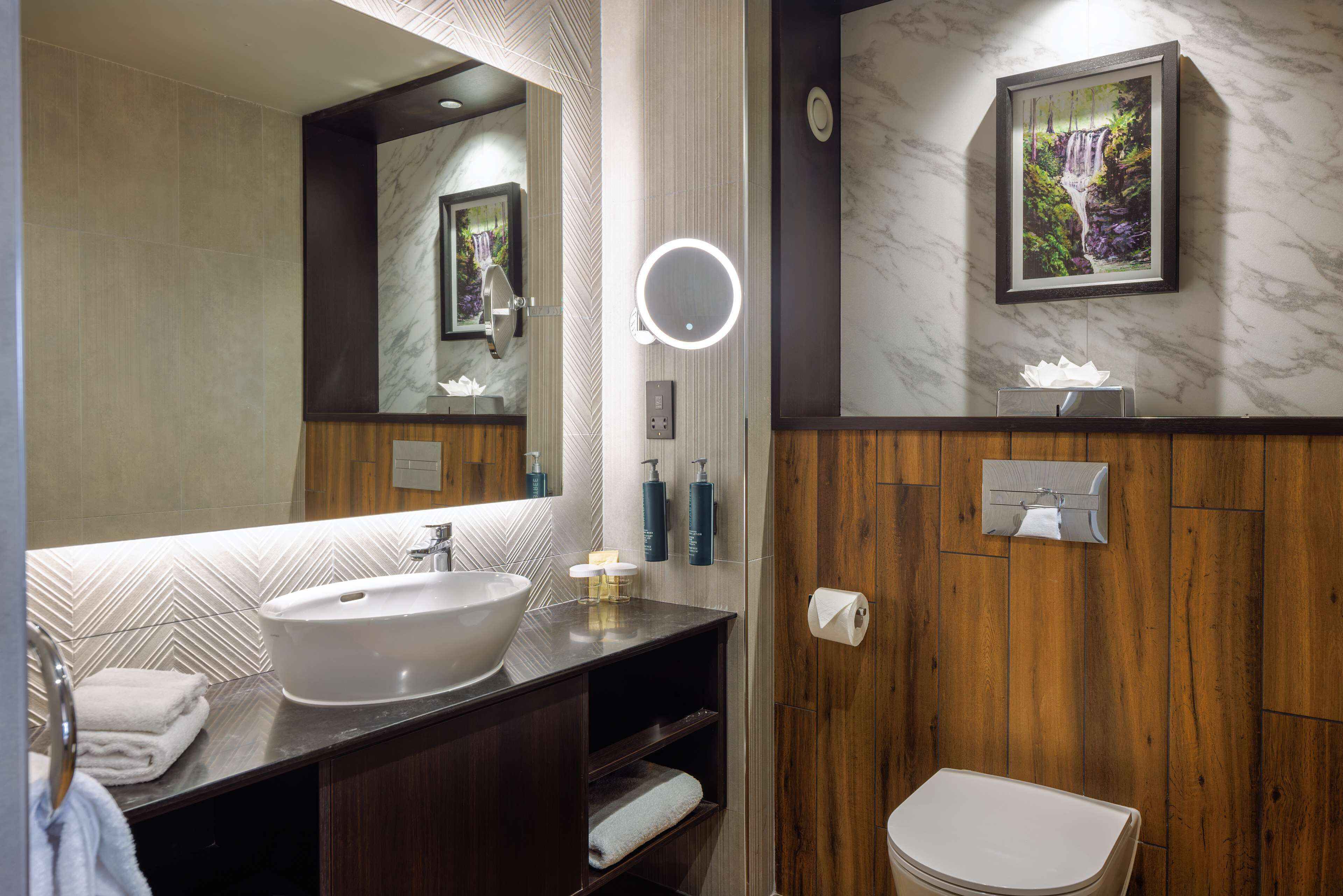 Un baño moderno con un espejo grande, un lavabo y un inodoro.