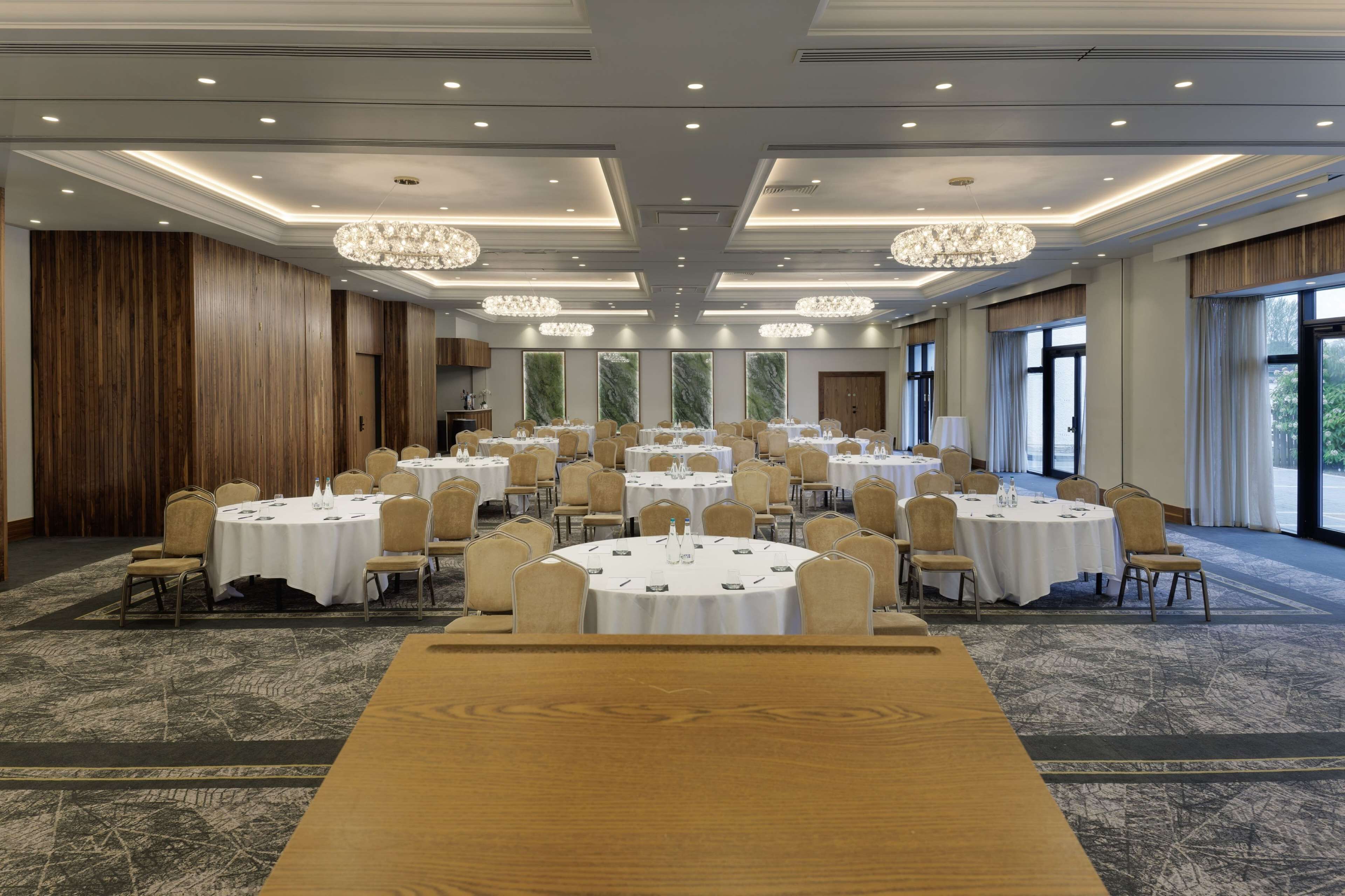 A conference room with round tables, chairs, and chandeliers.