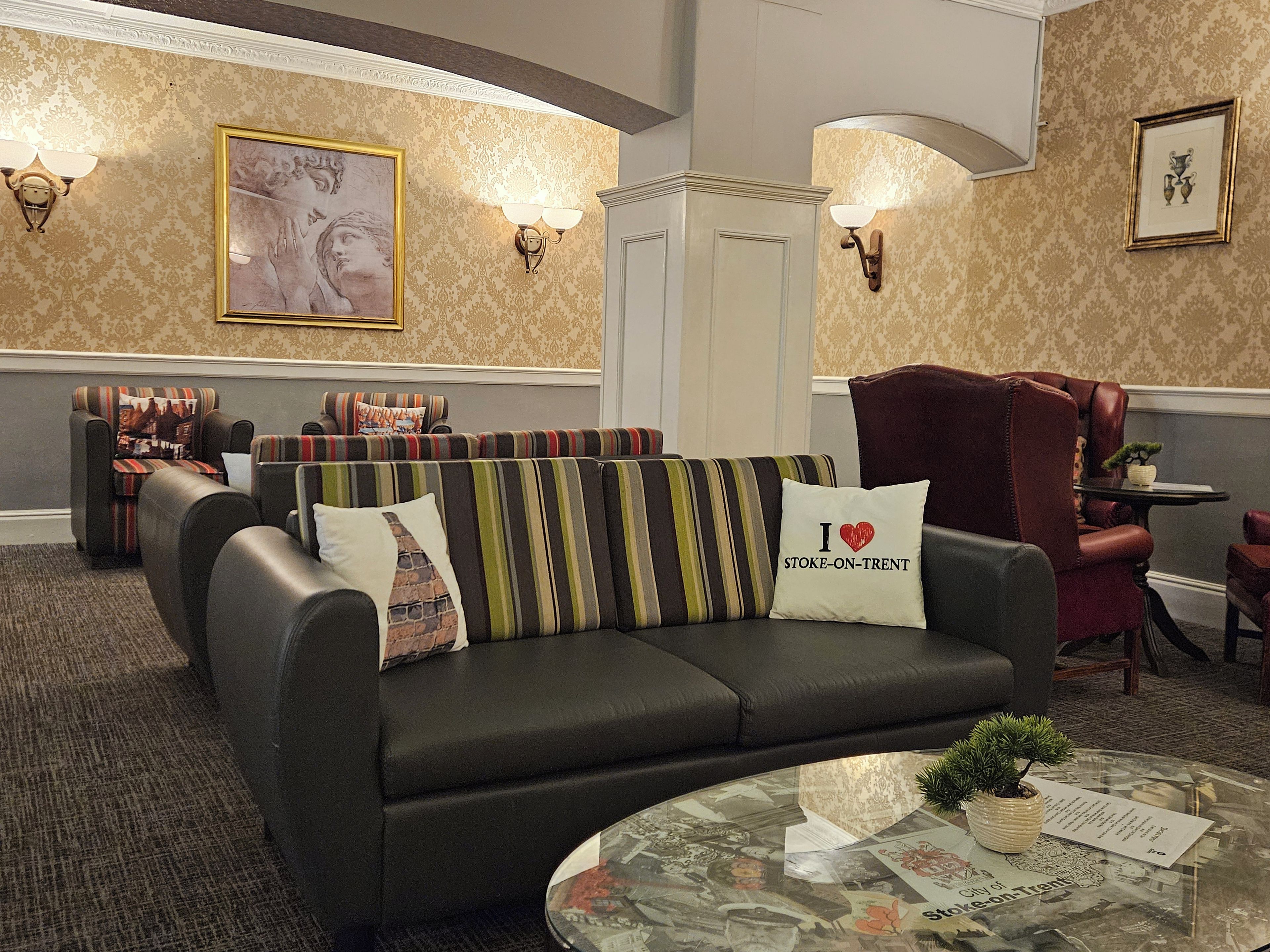 A modern lounge area with a sofa, armchairs, and a glass coffee table.