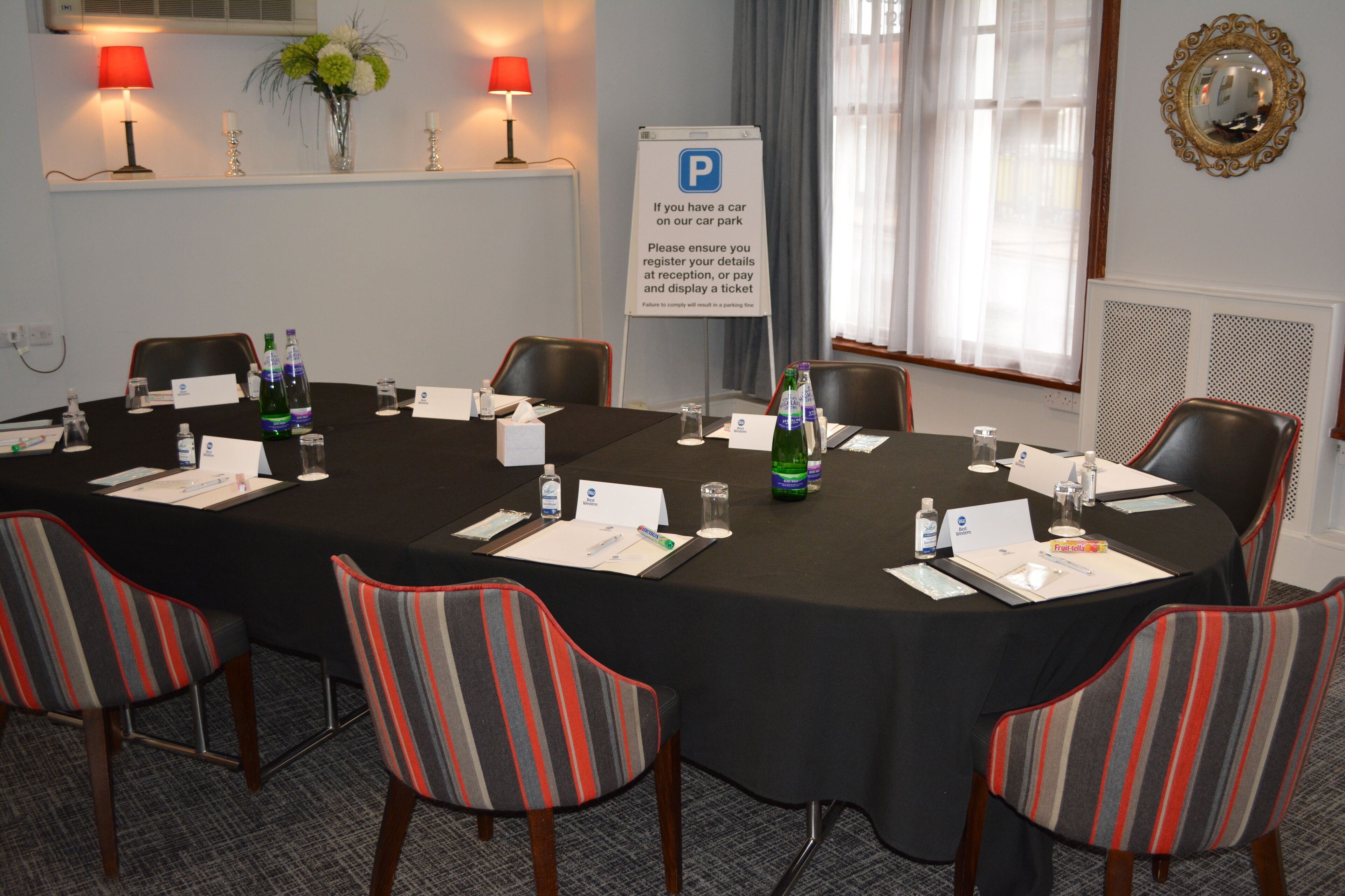 A conference room with a long table, chairs, name cards, water bottles, and a parking sign.