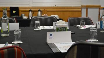 A conference room with a table set for a meeting, including nameplates, water bottles, and a tissue box.