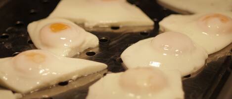A close-up of a grill with several pieces of food, likely eggs, being cooked.