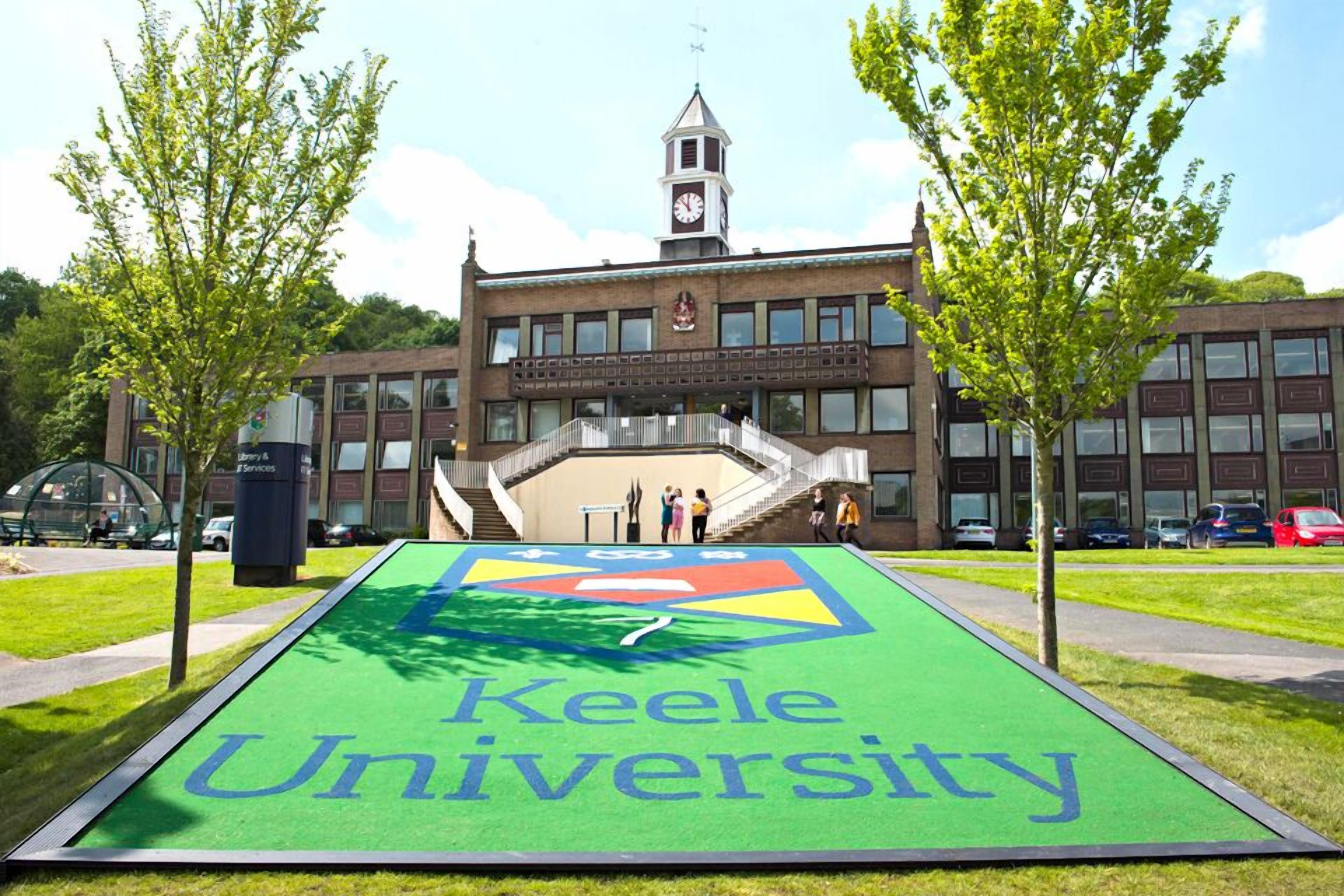 Campus de la Universidad Keele, con césped verde y un edificio al fondo.