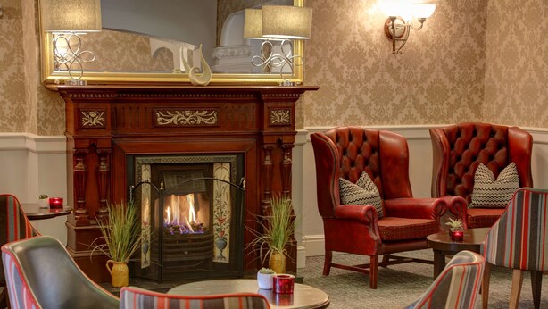 A cozy lounge area with a fireplace, leather armchairs, and striped sofas. - Best Western Stoke on Trent City Centre Hotel (Stoke-on-Trent)