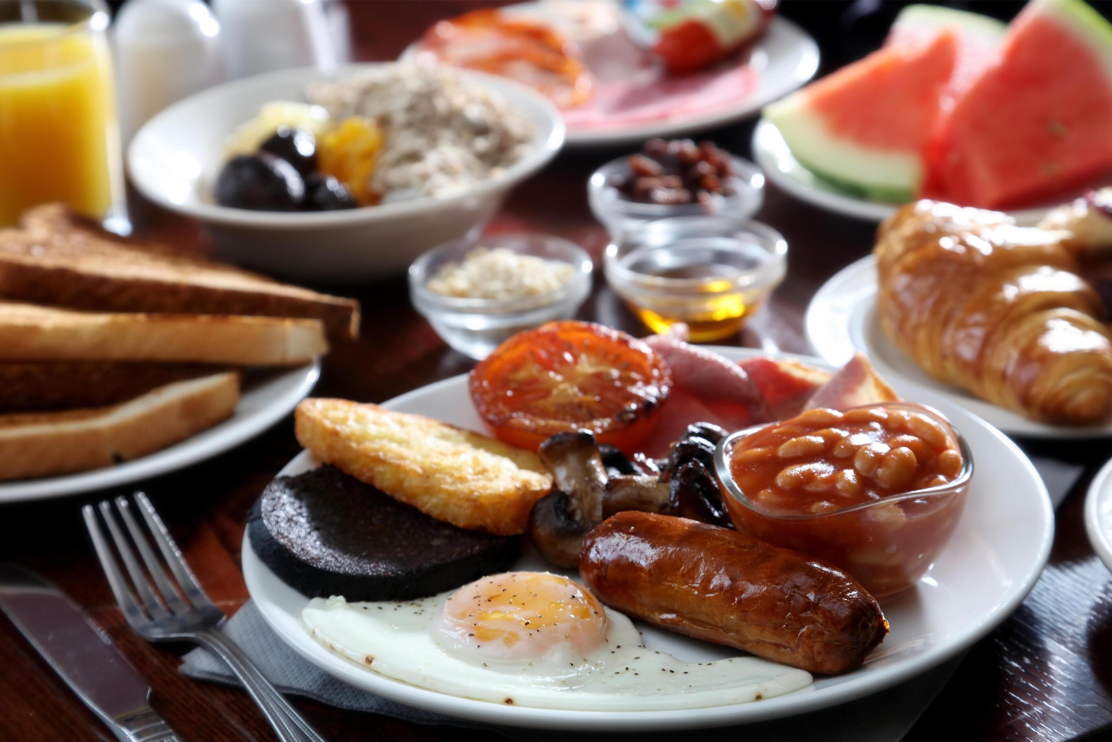 Un plato de desayuno con huevos, salchichas, tomates y tostadas.